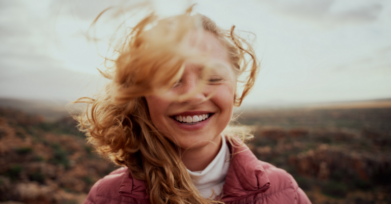 Young woman laughing, her hair blown by the wind