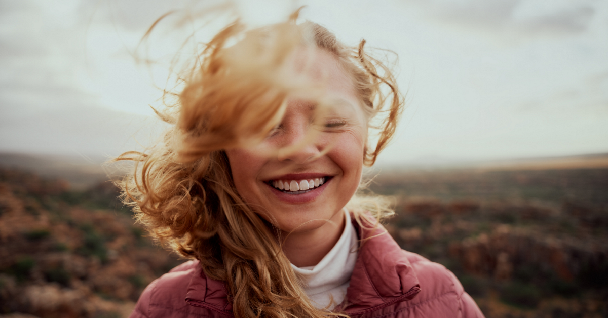 Young woman laughing, her hair blown by the wind